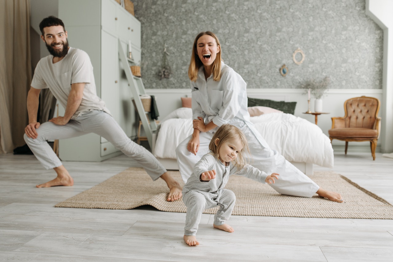 Mom and dad stretching with the baby in the bedroom.jpg